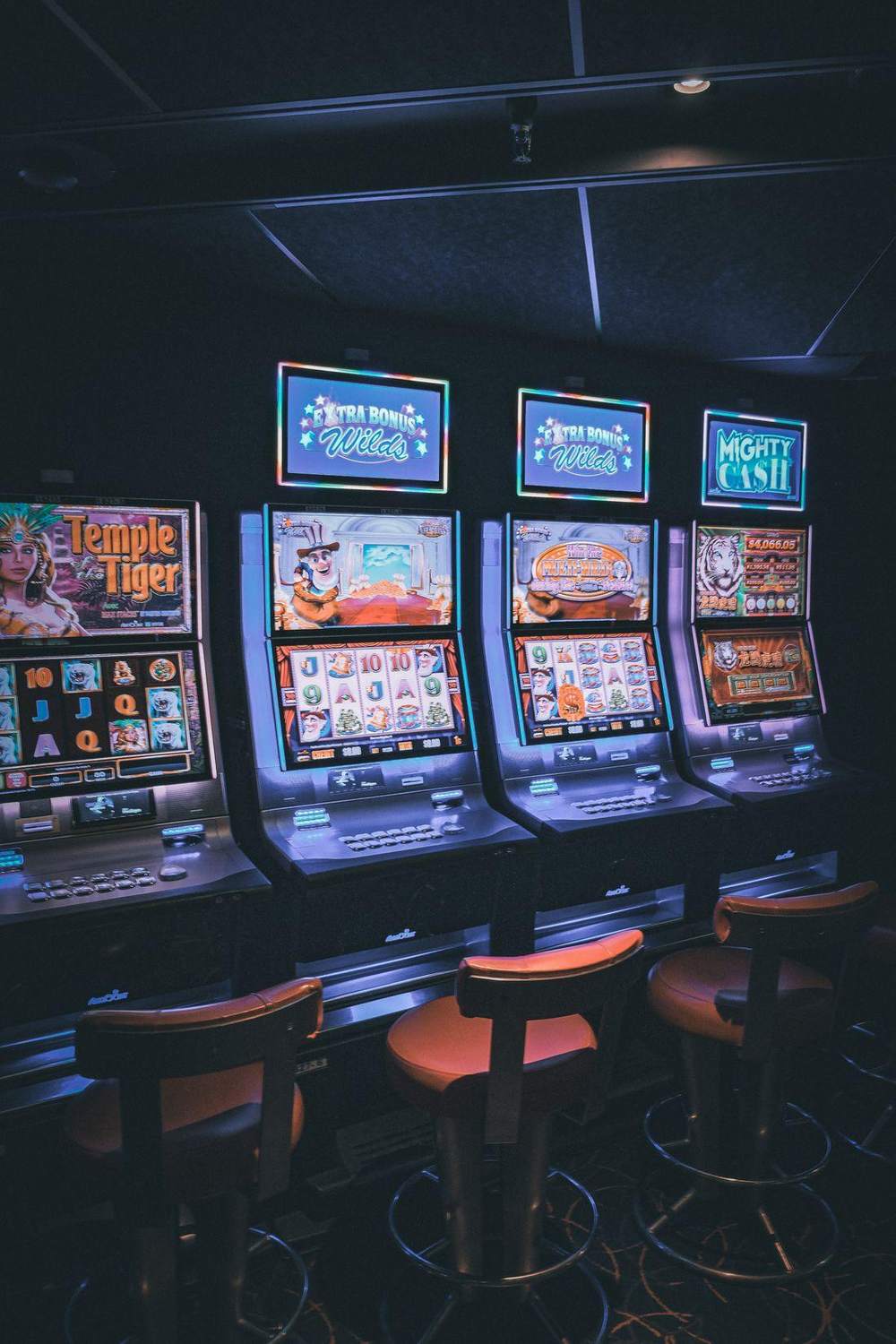 Barisan mesin slot menyala di ruang kasino yang temaram