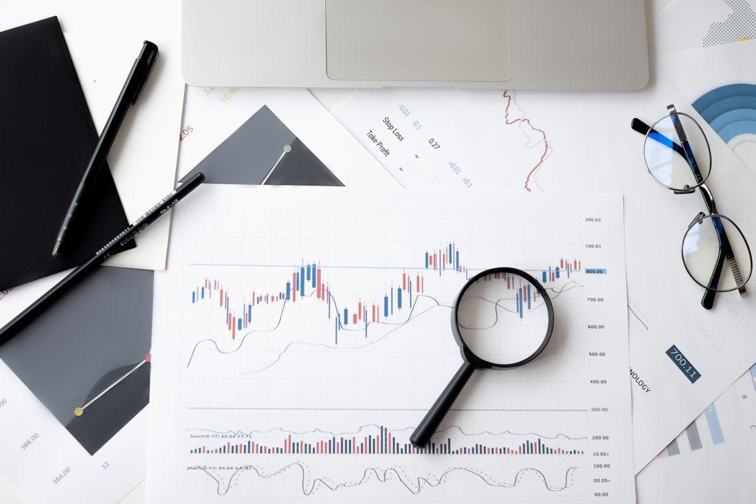 Kaca pembesar di atas dokumen analisis, melambangkan membaca syarat promo dengan cermat