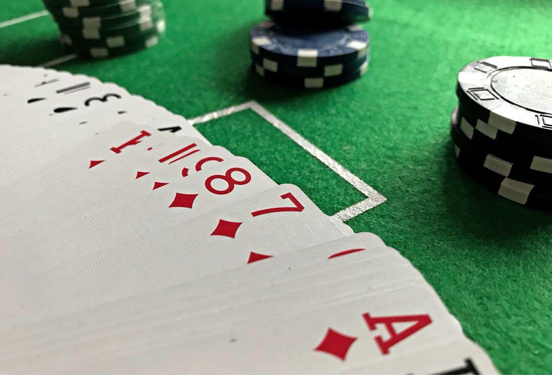 Dek kartu remi dan chip poker di atas meja felt hijau