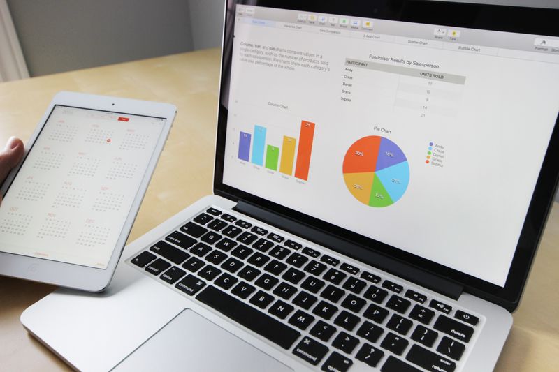 Laptop menampilkan grafik dan tablet kalender untuk perhitungan mingguan
